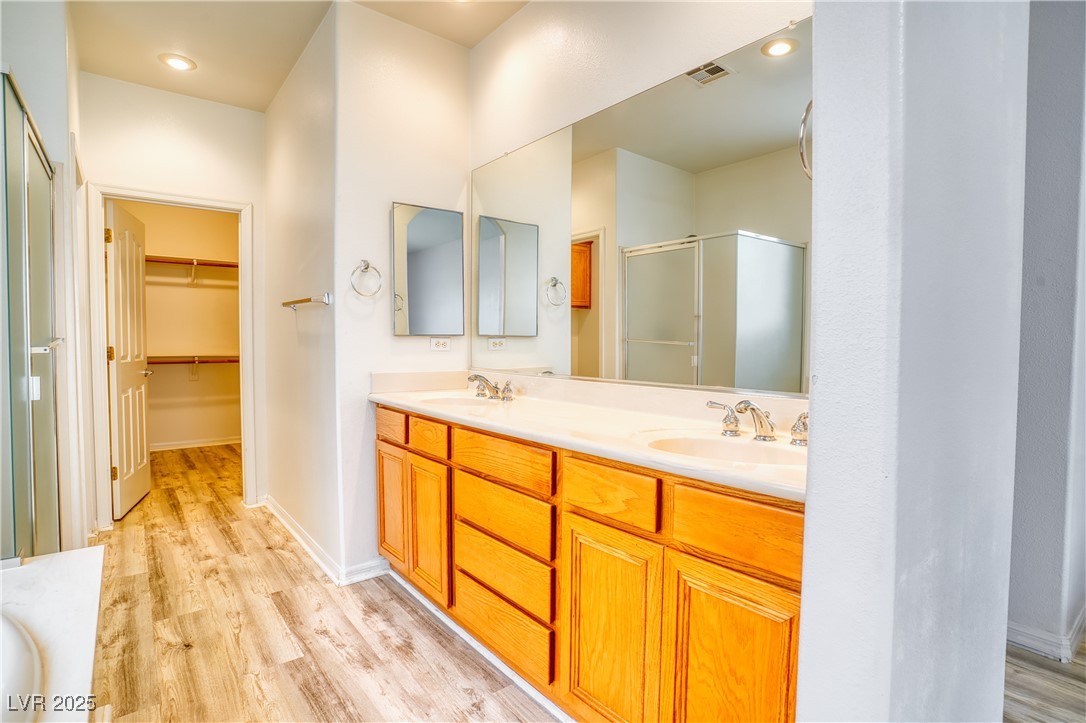2383 Rainswept Avenue Henderson, NV 89052 - Photo 26 of 62 Full bathroom with a shower stall, double vanity, light wood-style floors, a walk in closet, and recessed lighting