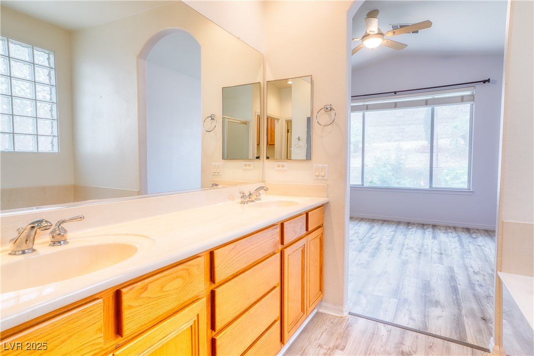 2383 Rainswept Avenue Henderson, NV 89052 - Photo 27 of 62 Full bath with double vanity, light wood finished floors, ceiling fan, vaulted ceiling, and a garden tub