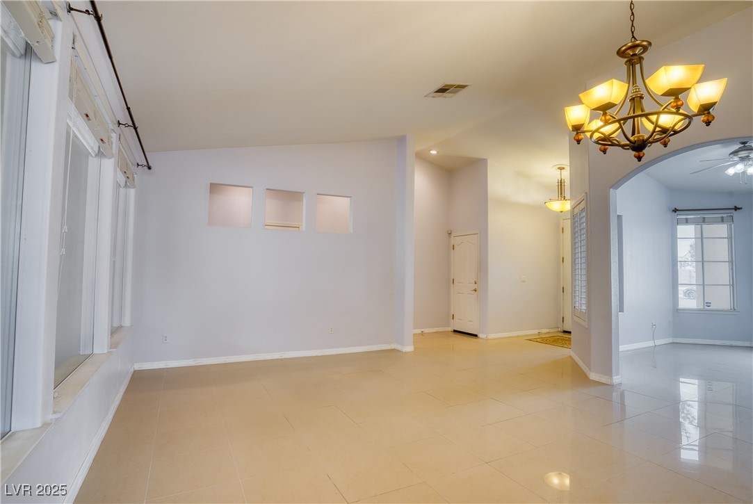 2383 Rainswept Avenue Henderson, NV 89052 - Photo 6 of 62 Empty room featuring lofted ceiling, arched walkways, light tile patterned floors, and a chandelier