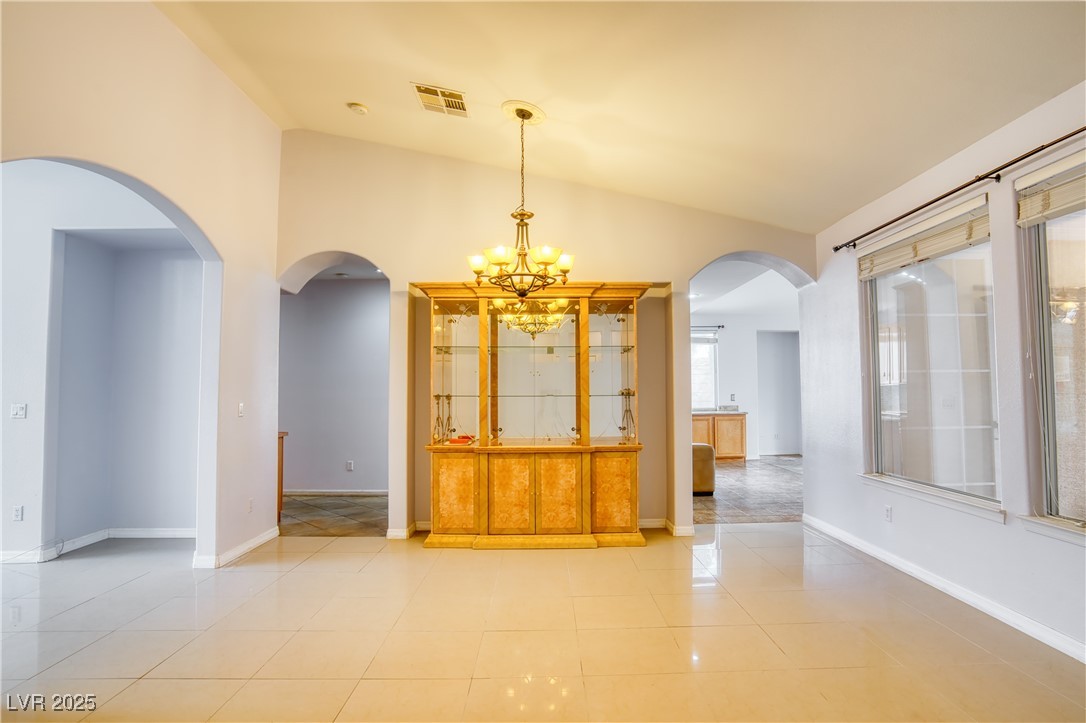 2383 Rainswept Avenue Henderson, NV 89052 - Photo 8 of 62 Unfurnished room with a chandelier, lofted ceiling, arched walkways, and light tile patterned floors