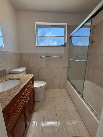 a bathroom with a granite countertop sink a toilet and a mirror