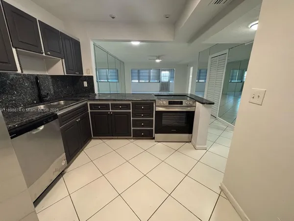 a kitchen with granite countertop a refrigerator and a stove top oven
