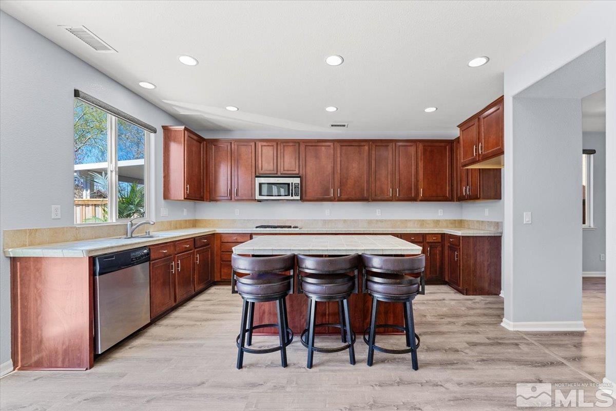11215 Torino Way Reno, NV 89521 - Photo 5 of 21 a kitchen with stainless steel appliances granite countertop wooden table chairs sink and stove