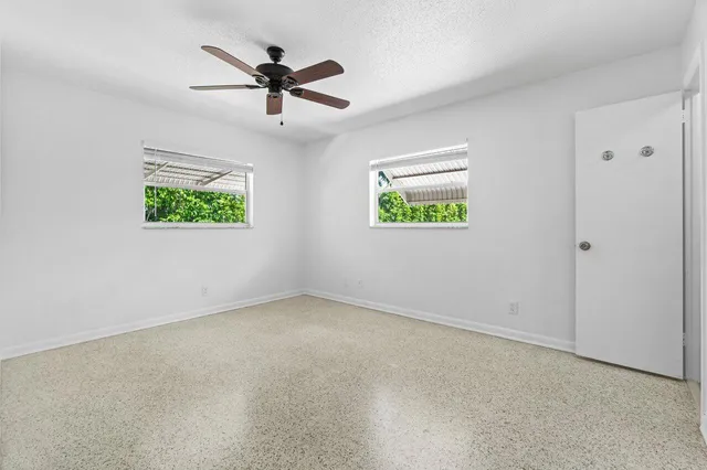 an empty room with window and ceiling fan