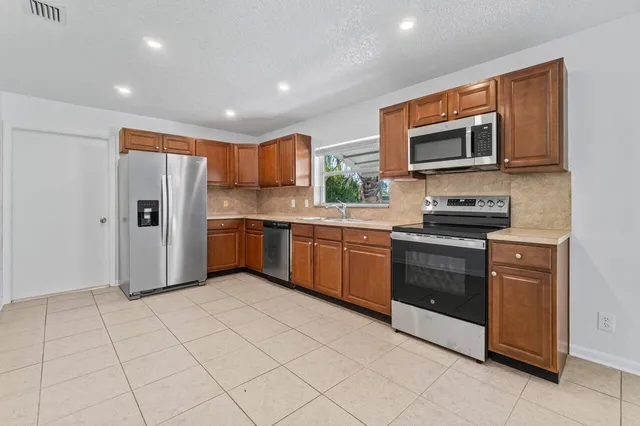 a kitchen with stainless steel appliances granite countertop a refrigerator and a stove top oven
