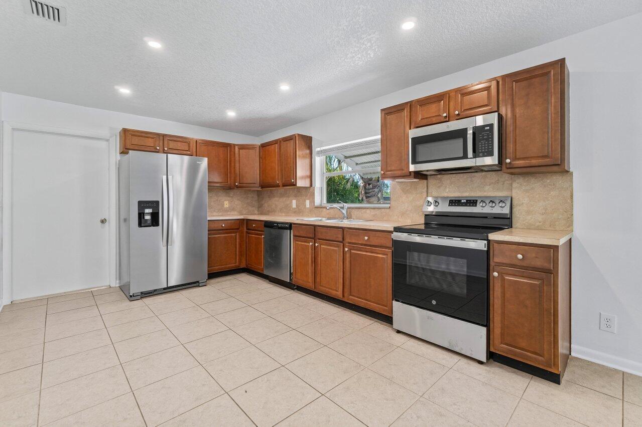 751 Hummingbird Way, Unit 7 North Palm Beach, FL 33408 - Photo 5 of 39 a kitchen with stainless steel appliances granite countertop a refrigerator and a stove top oven