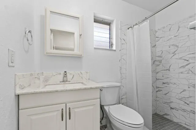 a bathroom with a granite countertop toilet sink and mirror