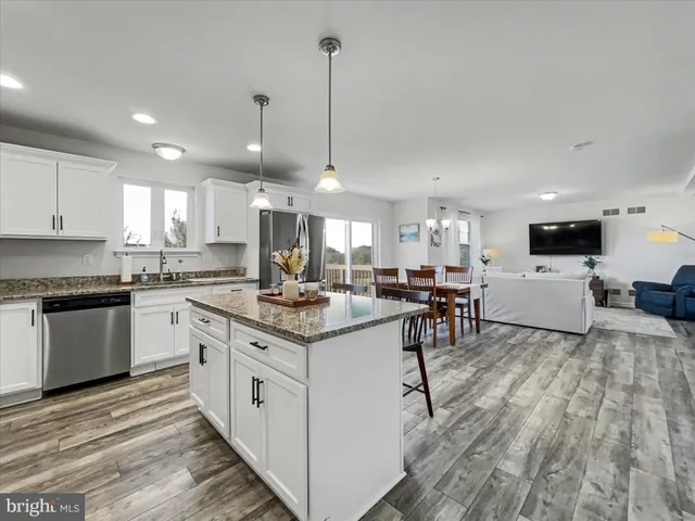 a kitchen with a stove a sink a kitchen island with chairs and wooden floor