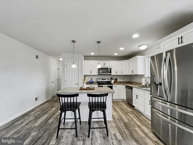 a kitchen with kitchen island a wooden floor and stainless steel appliances