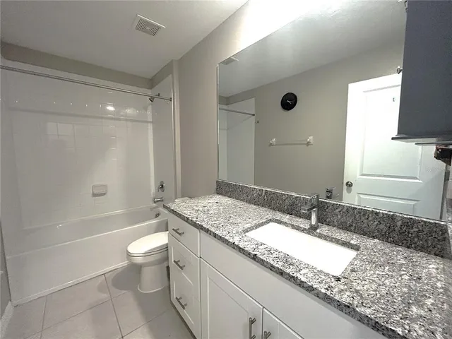 a bathroom with a granite countertop sink a toilet a mirror and bathtub