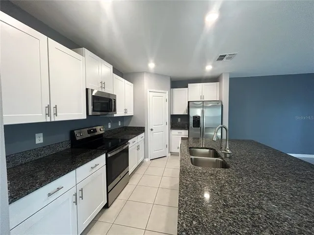 a large kitchen with stainless steel appliances a stove a sink and a microwave