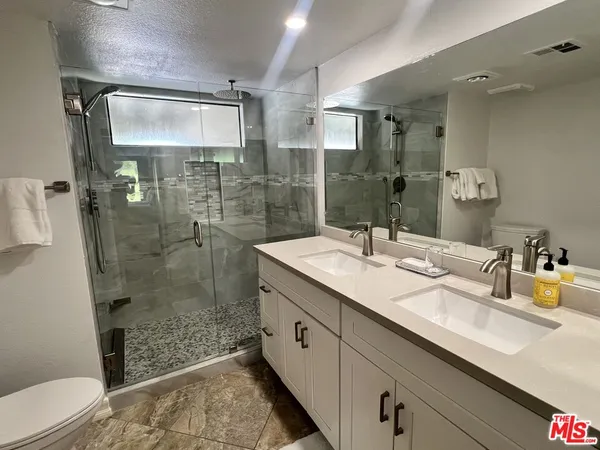 a bathroom with a granite countertop sink a toilet and shower