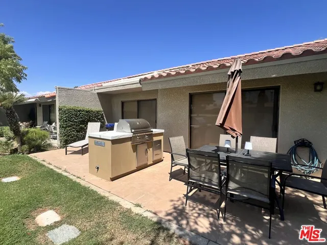 a view of a patio with table and chairs with a barbeque grill and a small yard