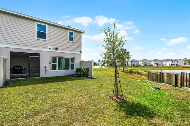 a view of a house with a yard and a large tree
