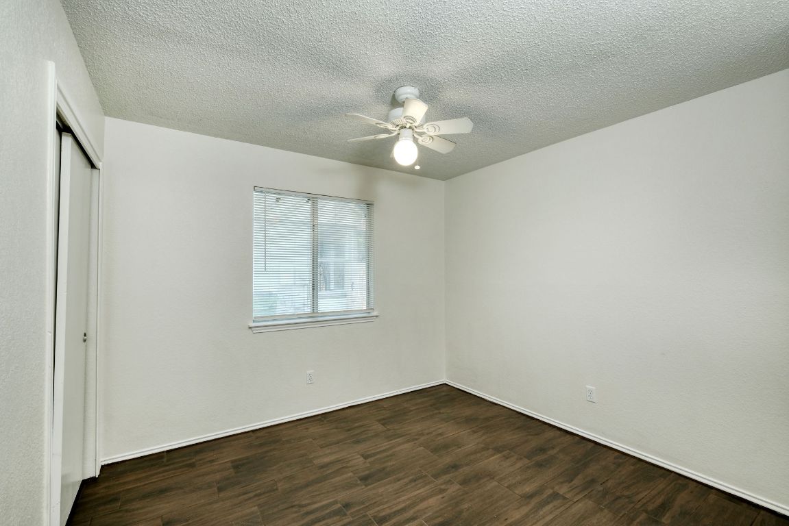 1304 Garden Path Cove Round Rock, TX 78664 - Photo 11 of 14 Unfurnished bedroom with dark wood-type flooring, a textured ceiling, a closet, and a ceiling fan