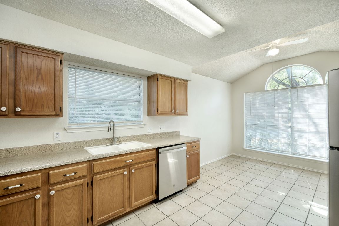 1304 Garden Path Cove Round Rock, TX 78664 - Photo 4 of 14 Kitchen featuring light tile patterned floors, stainless steel appliances, a textured ceiling, a ceiling fan, and lofted ceiling