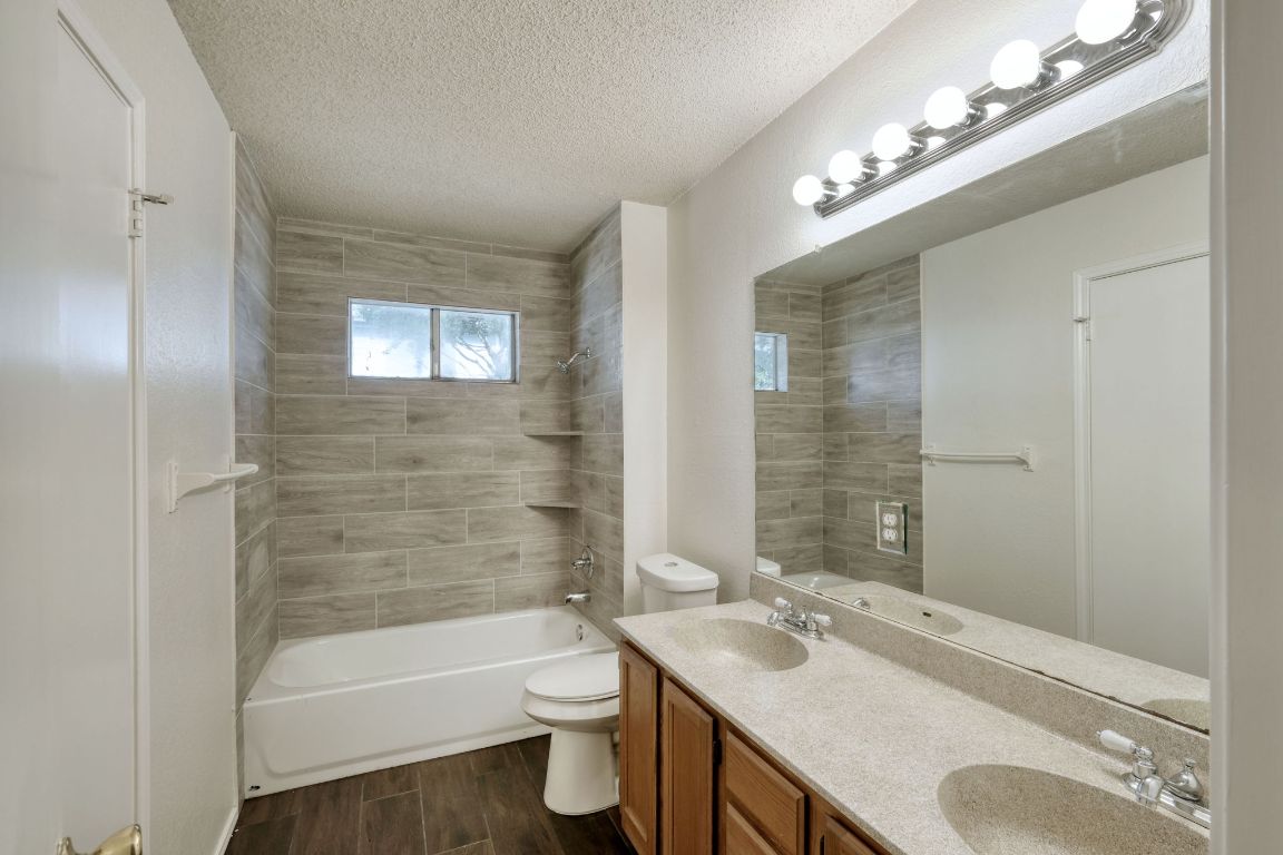 1304 Garden Path Cove Round Rock, TX 78664 - Photo 8 of 14 Full bathroom featuring wood tiled floors, tub / shower combination, double vanity, and a textured ceiling