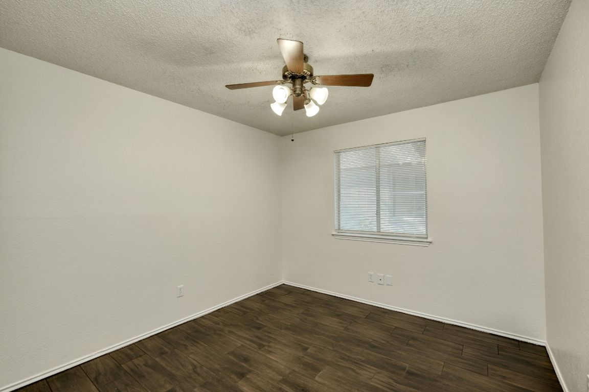 1304 Garden Path Cove Round Rock, TX 78664 - Photo 9 of 14 Empty room with dark wood-type flooring, a textured ceiling, and a ceiling fan