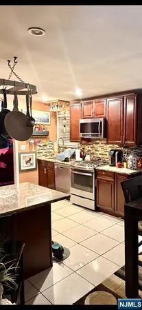 a kitchen with stainless steel appliances kitchen island granite countertop a sink stove and refrigerator