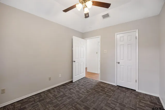 a view of an empty room and chandelier fan