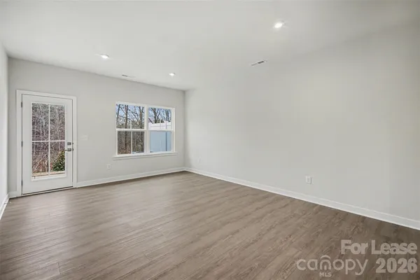 a view of an empty room with wooden floor and windows