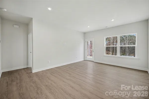 a view of an empty room with wooden floor and windows