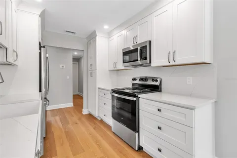 a kitchen with stainless steel appliances kitchen island granite countertop a stove a refrigerator and a view of living room