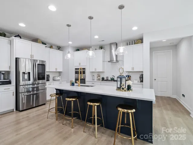 a kitchen with stainless steel appliances granite countertop a sink a stove a refrigerator and chairs