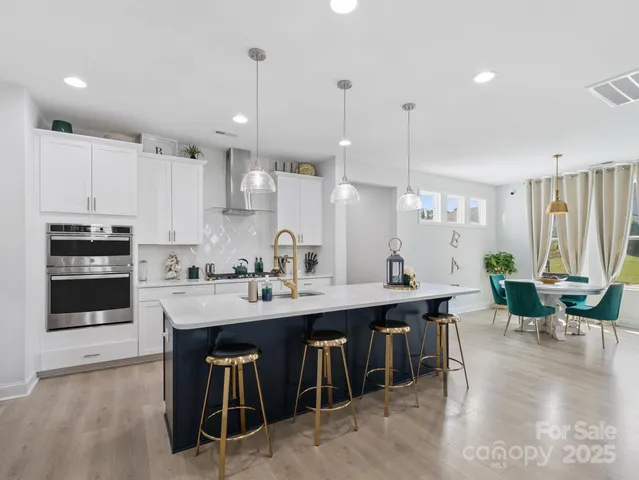 a kitchen with stainless steel appliances granite countertop a stove a sink a oven a dining table and chairs