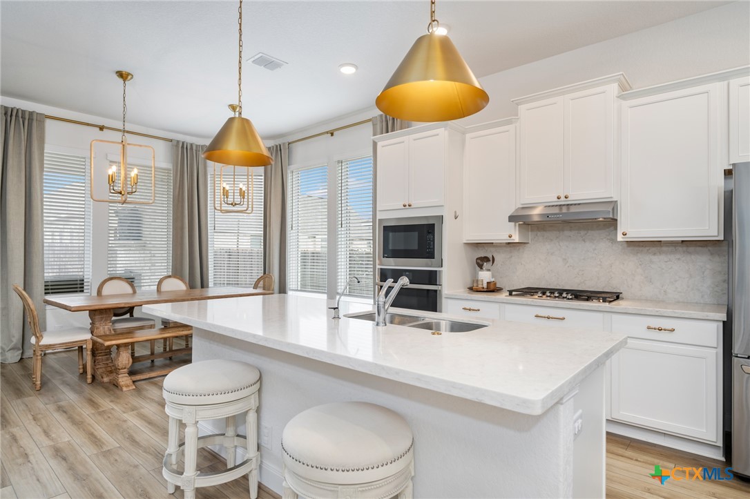 2939 Rems New Braunfels, TX 78130 - Photo 17 of 41 a kitchen with a stove a refrigerator a sink a dining table and chairs with wooden floor