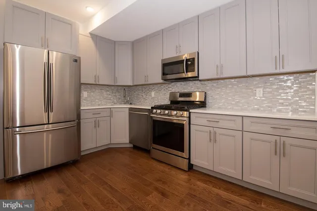 a kitchen with cabinets stainless steel appliances and wooden floor