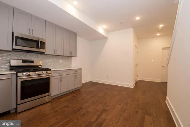a kitchen with stainless steel appliances granite countertop a stove a microwave and a hard wood floors