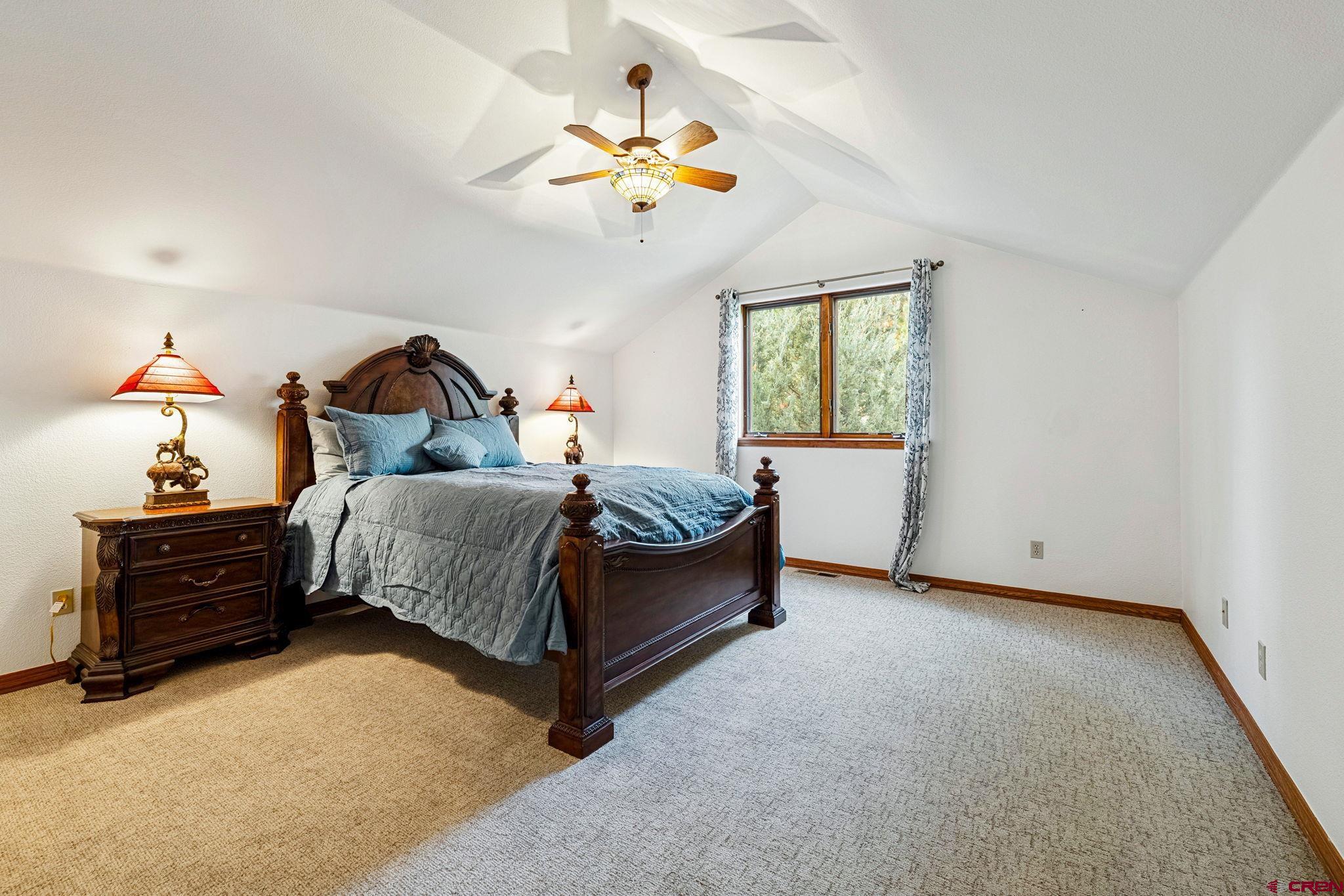 345 Red Rock Road Durango, CO 81301 - Photo 24 of 44 a bedroom with a bed and a chandelier