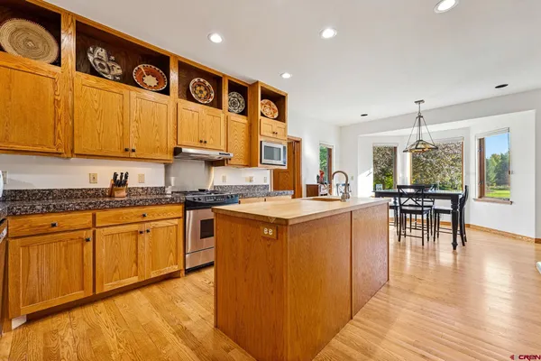 a kitchen with stainless steel appliances granite countertop wooden cabinets a sink and dishwasher a stove with wooden floor