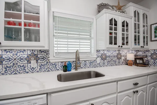 a large white kitchen with stainless steel appliances kitchen island granite countertop a large center island and a couch