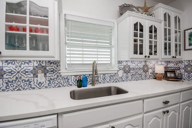 a large white kitchen with stainless steel appliances kitchen island granite countertop a large center island and a couch