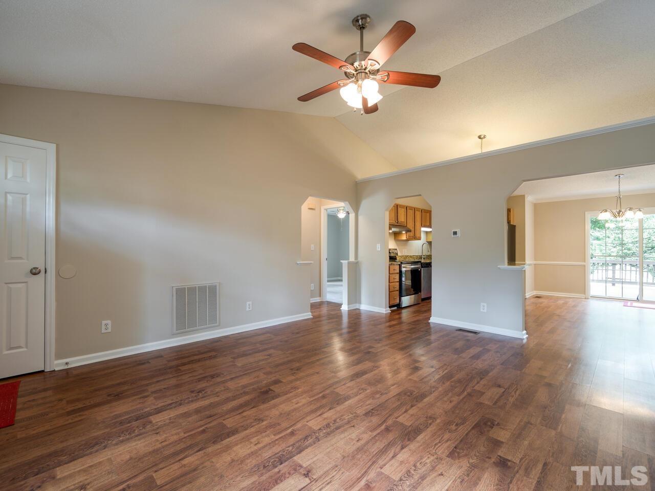 745 Brewer Circle Wake Forest, NC 27587 - Photo 11 of 43 an empty room with wooden floor chandelier fan and windows