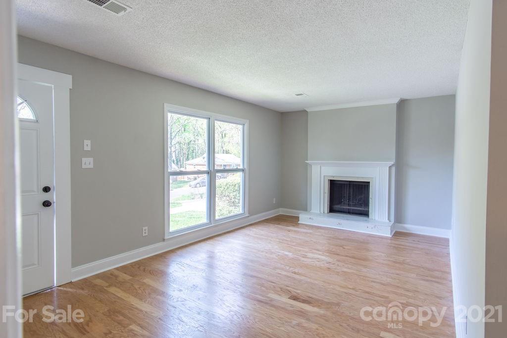 721 Rome Court Charlotte, NC 28209 - Photo 3 of 21 an empty room with wooden floor fireplace and windows