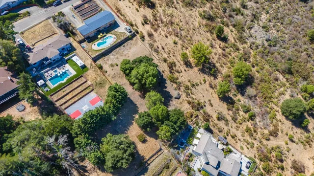 an aerial view of residential house with outdoor space and trees all around