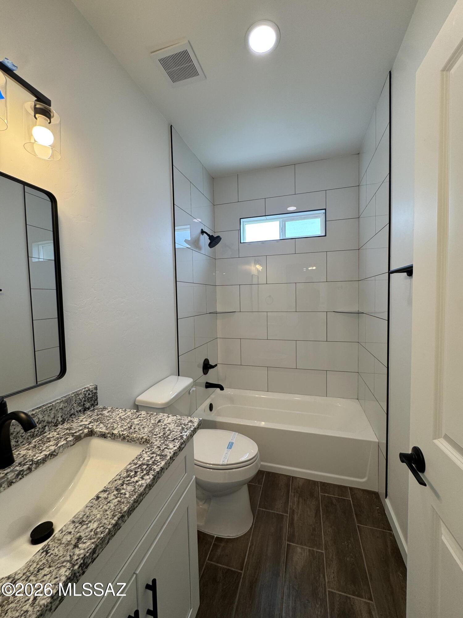 2130 North Ralph Avenue, Unit 1 Tucson, AZ 85712 - Photo 4 of 11 a bathroom with a granite countertop sink toilet and shower