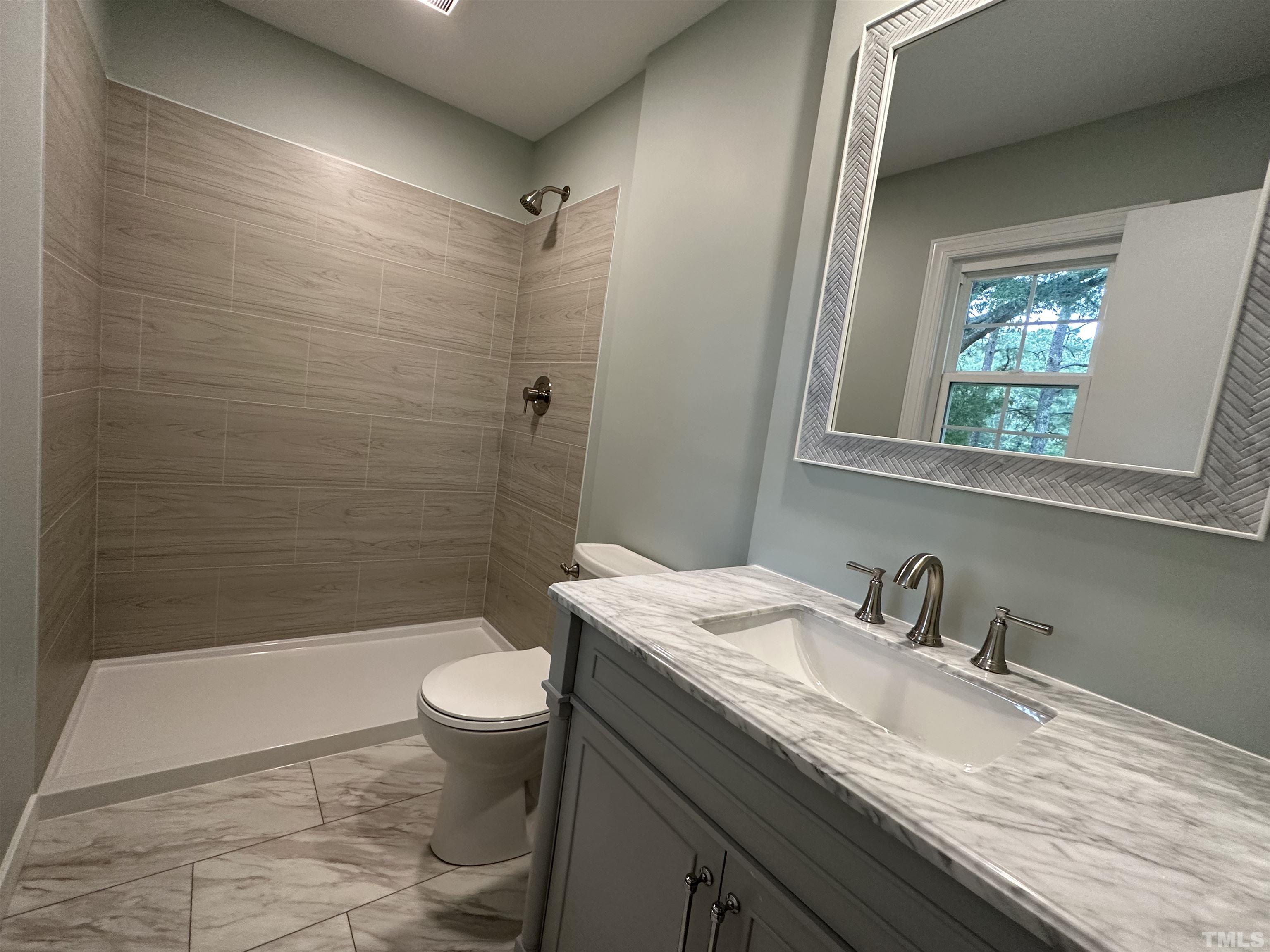 8904 Ransdell Road Raleigh, NC 27603 - Photo 19 of 23 a bathroom with a granite countertop sink a toilet a mirror and shower