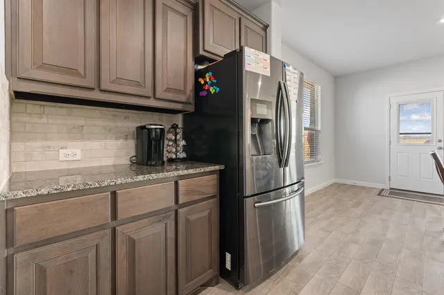 a kitchen with stainless steel appliances granite countertop a refrigerator a stove a sink a dining table and chairs