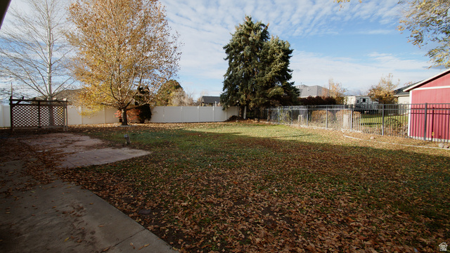 2455 South Bluff Road Syracuse, UT 84075 - Photo 35 of 35 Expansive fenced yard with mature trees, established lawn, concrete patio, and a dedicated storage shed