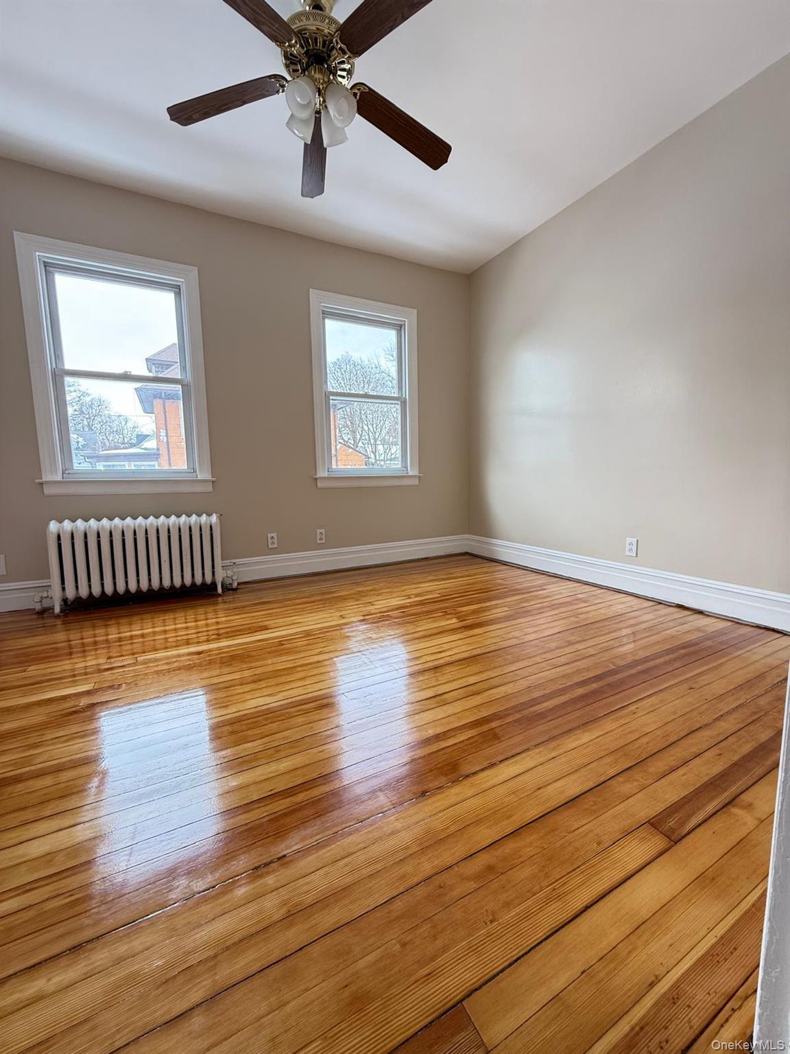 7 Flower Street New Rochelle, NY 10801 - Photo 5 of 13 an empty room with wooden floor chandelier fan and windows