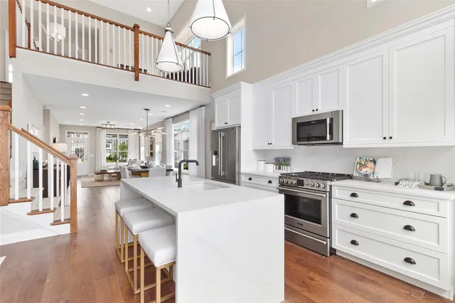 a kitchen with stainless steel appliances kitchen island granite countertop a sink a stove a dining table and chairs with wooden floor