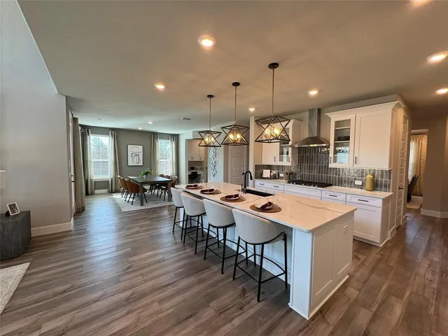 a large white kitchen with wooden floor and a large window