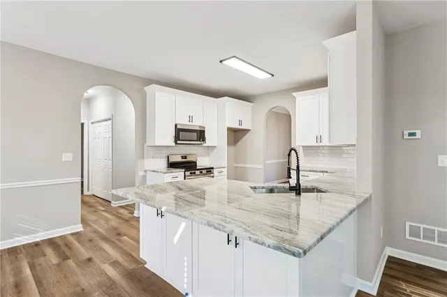 a kitchen with granite countertop a sink cabinets and stainless steel appliances