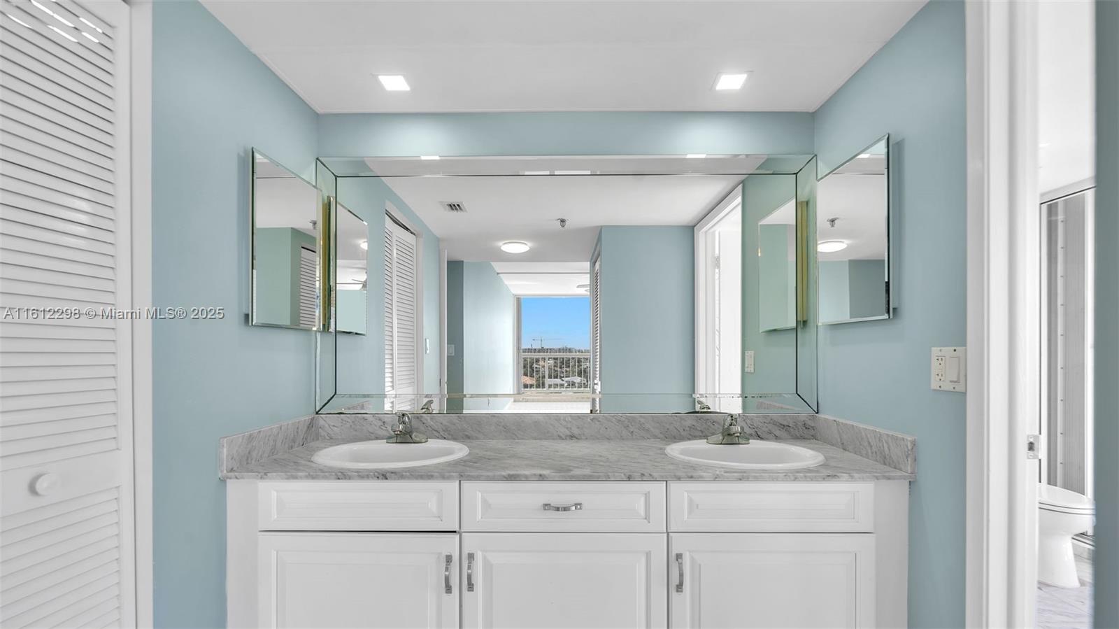 9341 Collins Avenue, Unit 707 Surfside, FL 33154 - Photo 11 of 55 a bathroom with a granite countertop sink a mirror and a