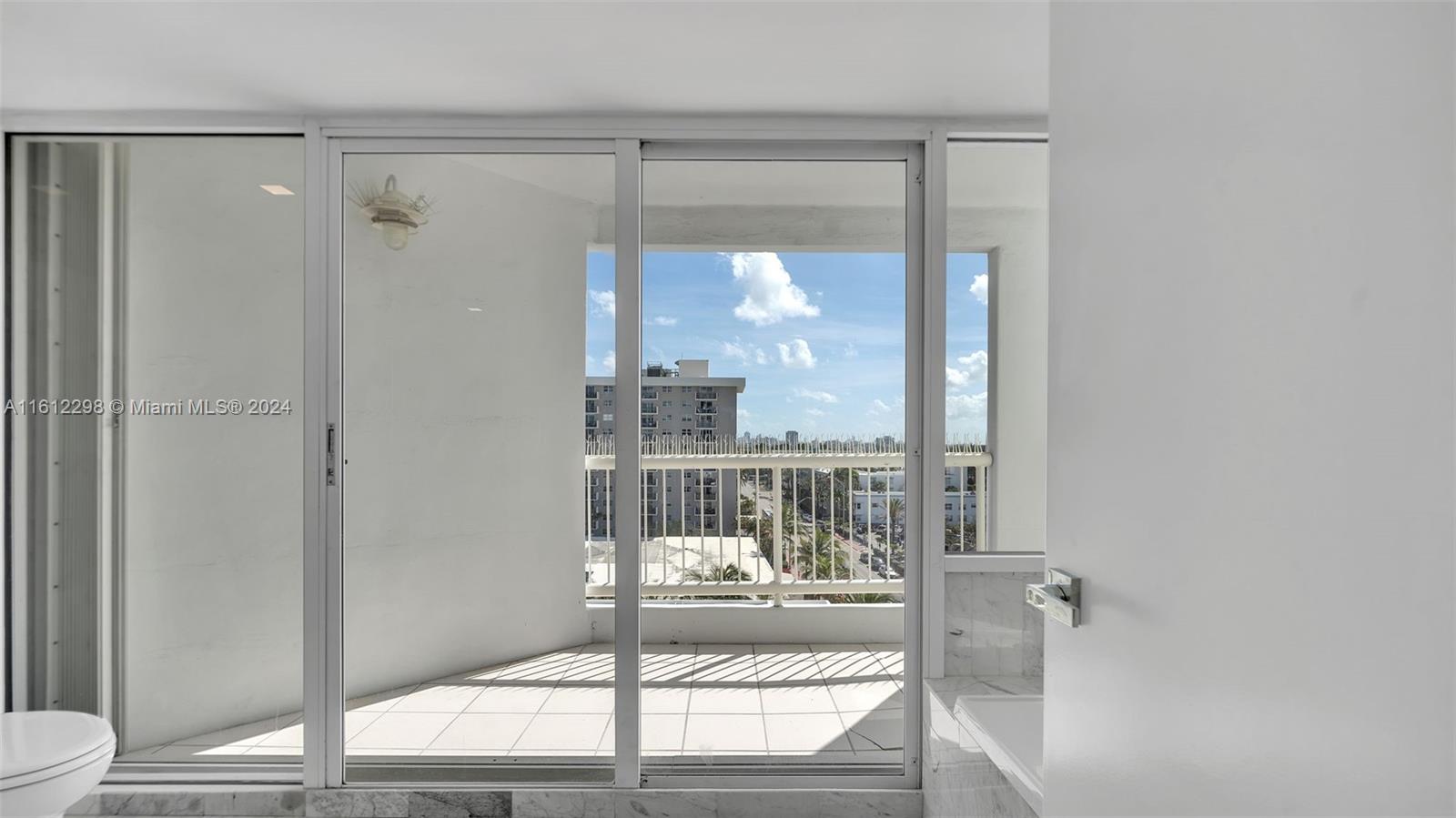 9341 Collins Avenue, Unit 707 Surfside, FL 33154 - Photo 42 of 55 a bathroom with a glass shower door and a window