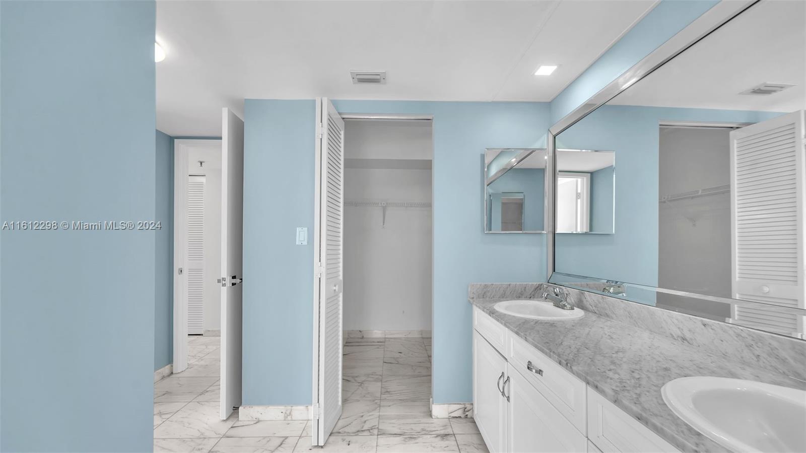 9341 Collins Avenue, Unit 707 Surfside, FL 33154 - Photo 47 of 55 a bathroom with a granite countertop sink and mirror
